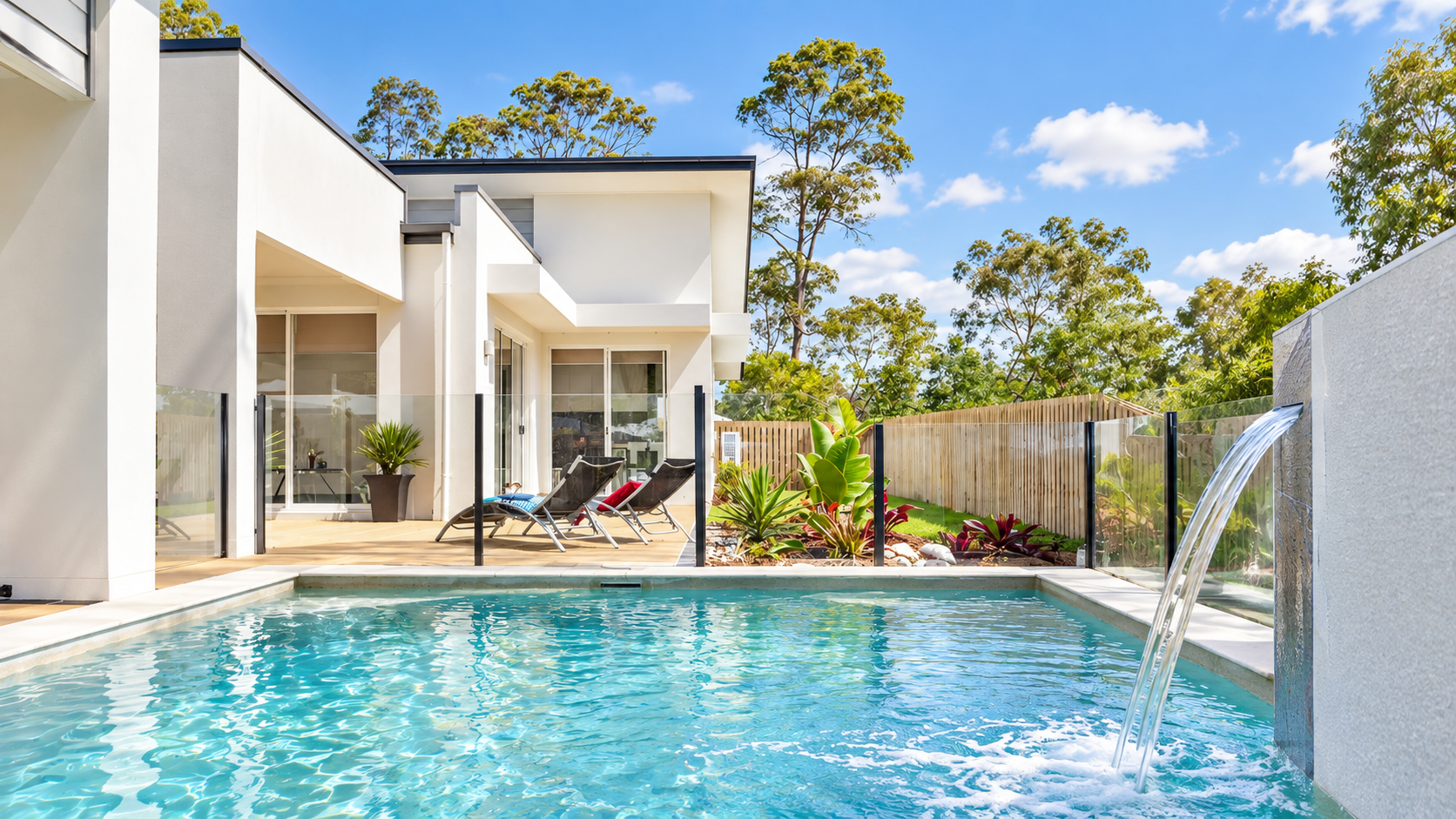 Semi-frameless glass pool fencing with slim black aluminium posts around a turquoise pool beside a modern Australian home